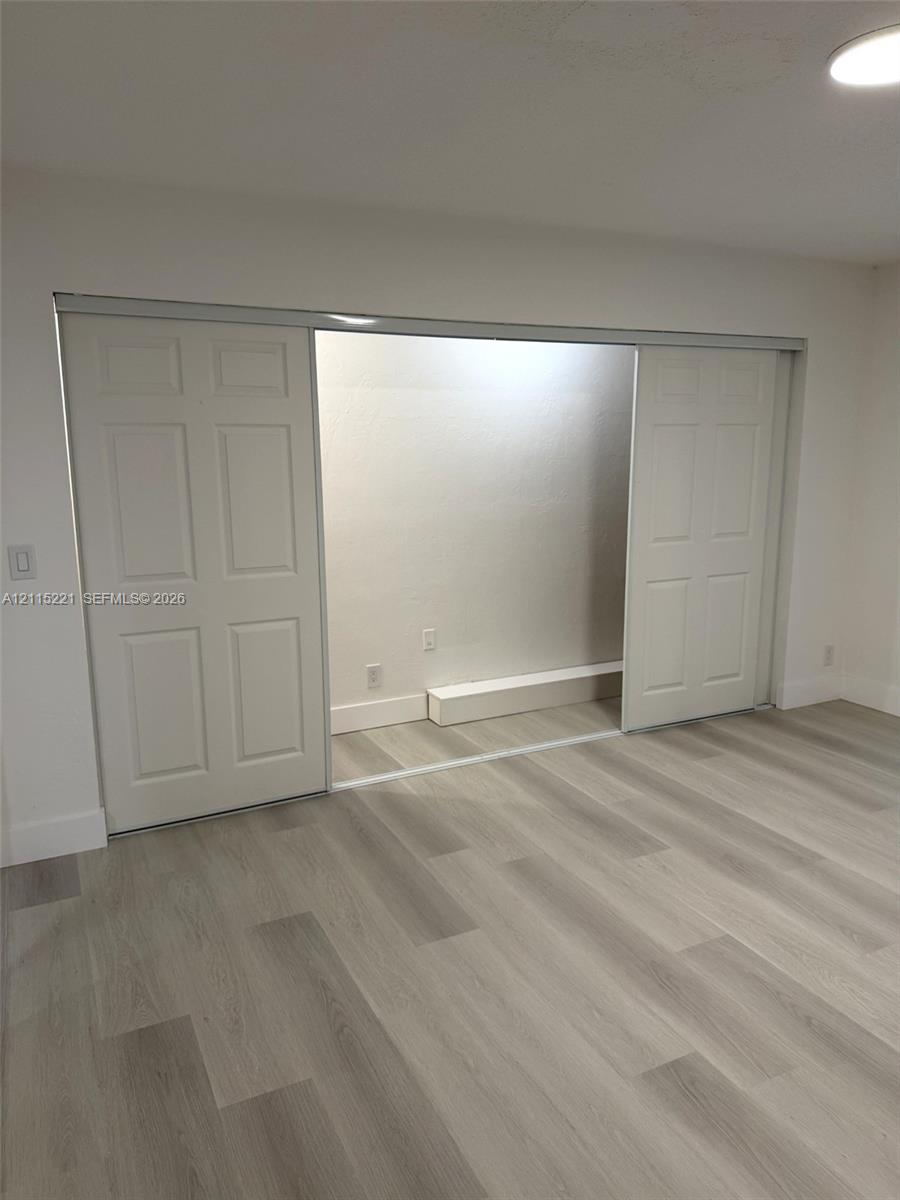 Wood-finish flooring, white four-panel sliding closet doors, and recessed ceiling lighting