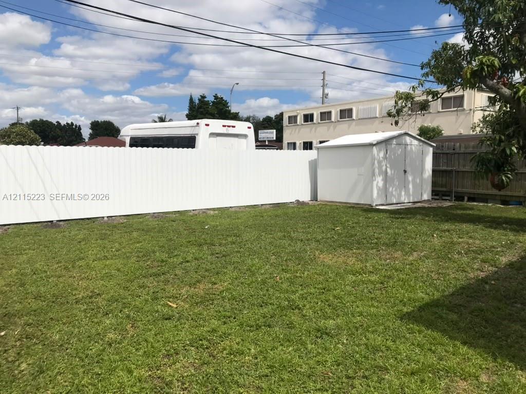 Fenced backyard featuring a manicured lawn and an exterior storage structure