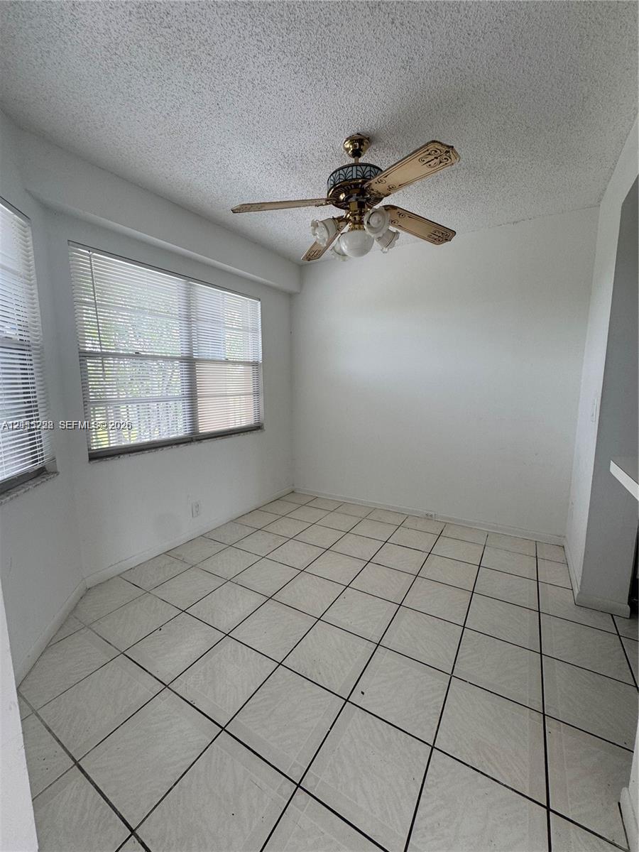 Ceramic tile flooring, multi-pane windows with horizontal blinds, and a central ceiling fan with integrated lighting