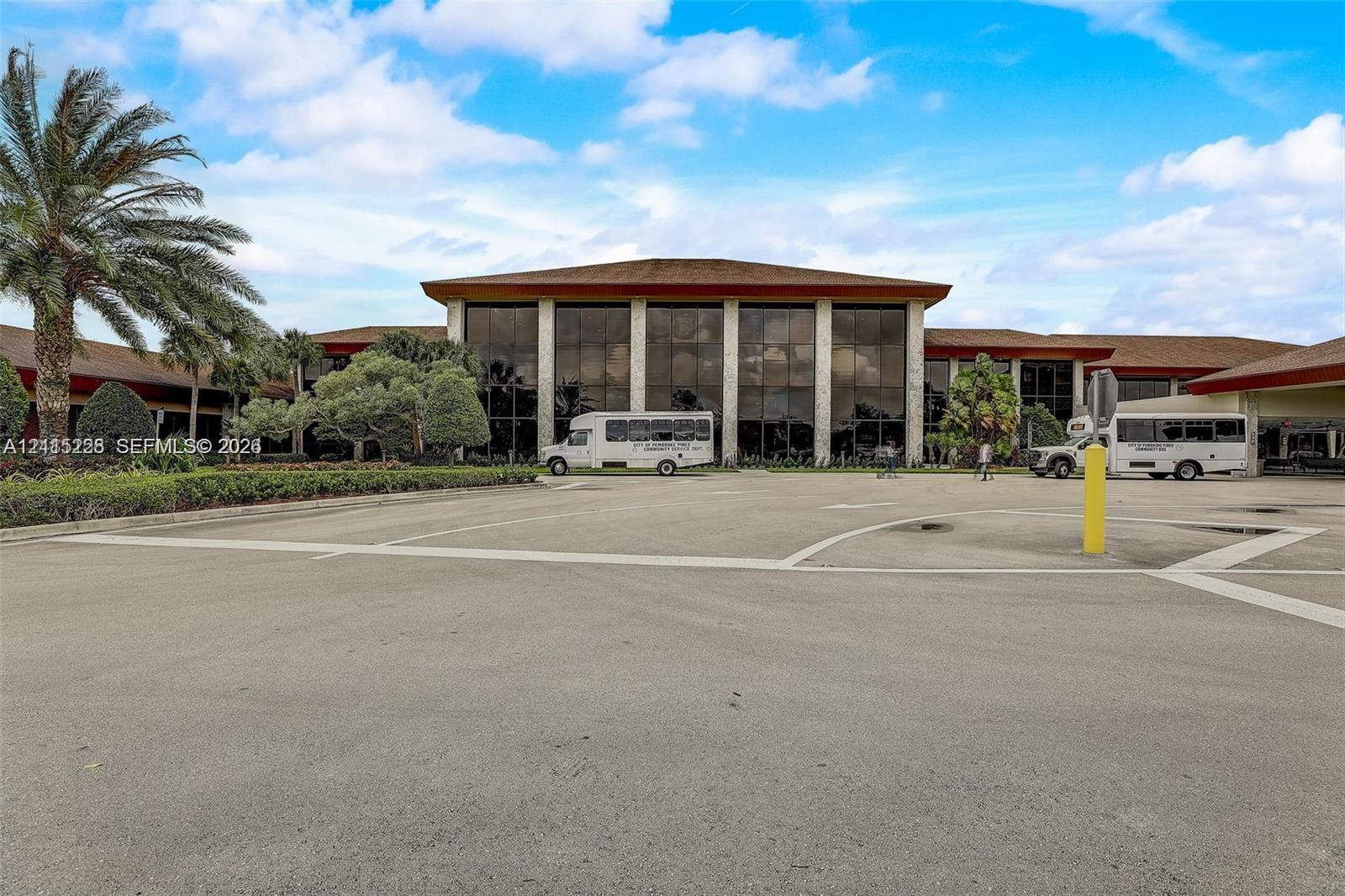 Expansive multi-story exterior featuring floor-to-ceiling glass paneling, stone masonry columns, and a wide paved arrival area