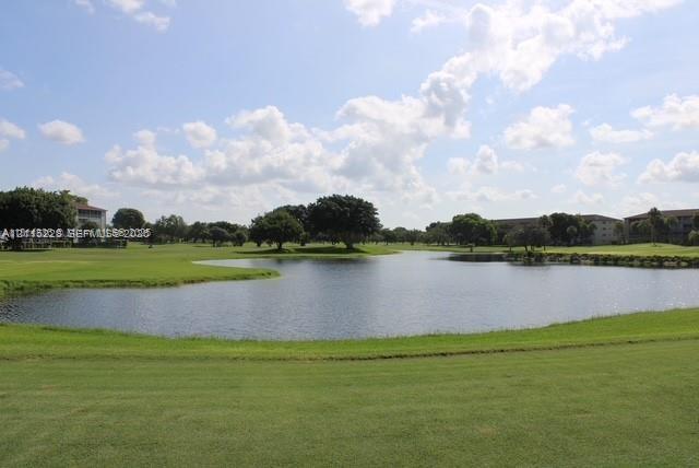 Waterfront grounds featuring a manicured lawn, pond, and mature trees