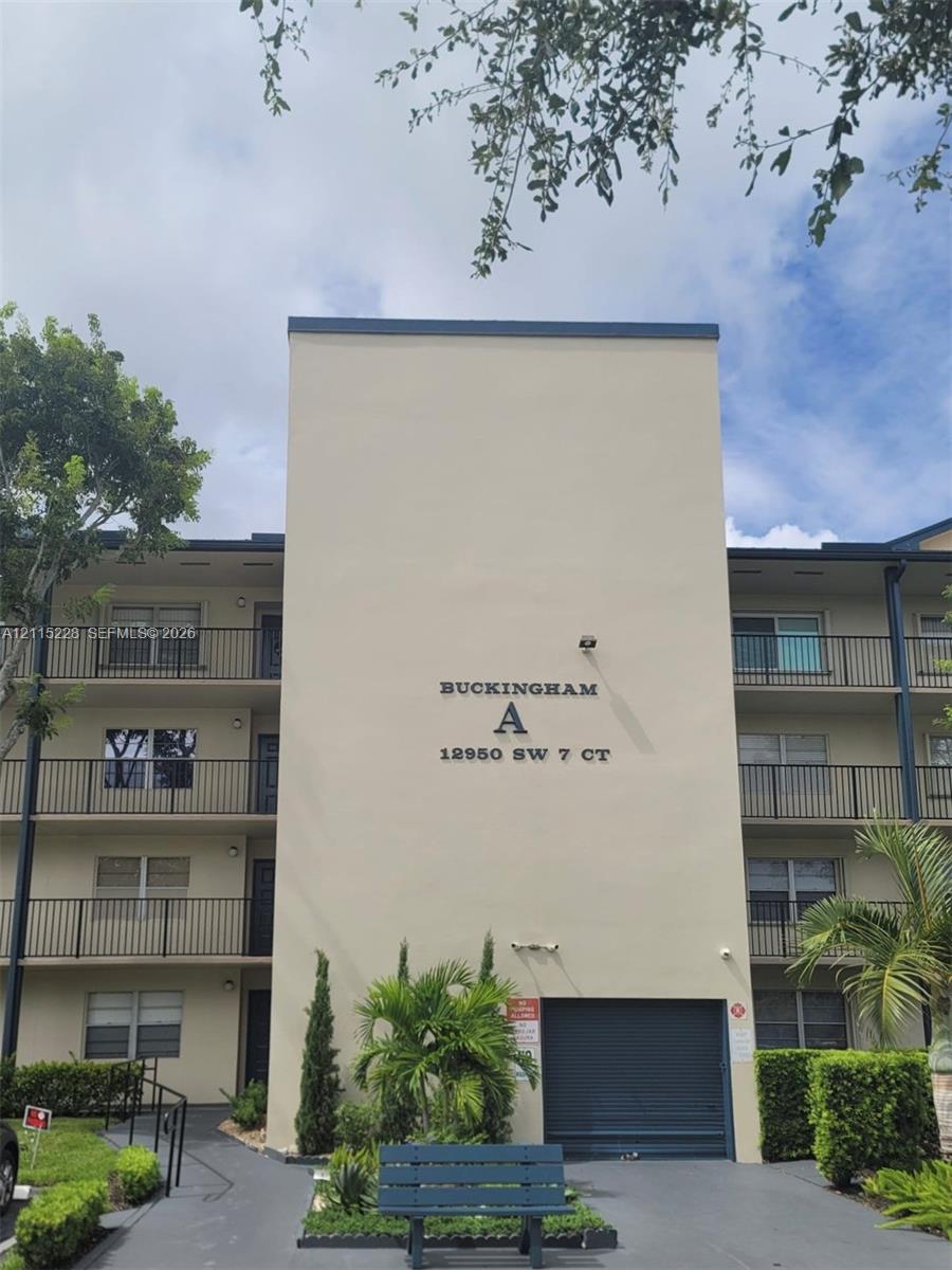 Multi-story residential building featuring smooth stucco exterior, decorative metal balcony railings, and ground-level garage access