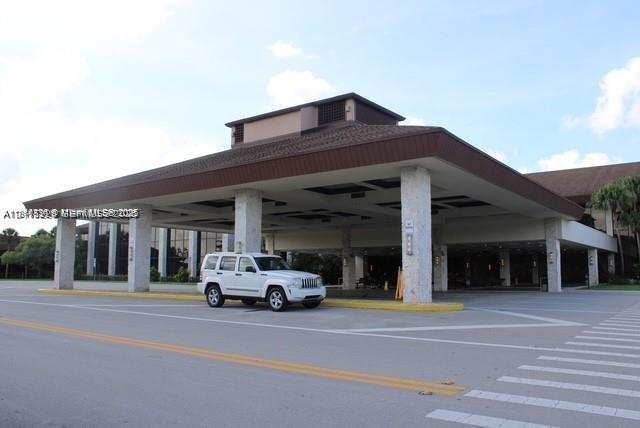 Covered porte-cochre entrance featuring stone-clad structural columns and a wide paved driveway