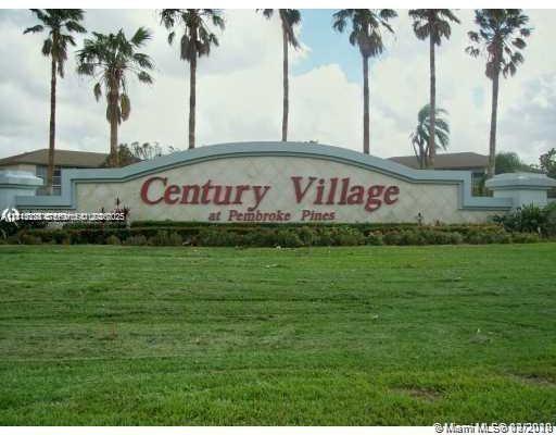 Community monument sign featuring architectural masonry, decorative detailing, and mature palm tree landscaping