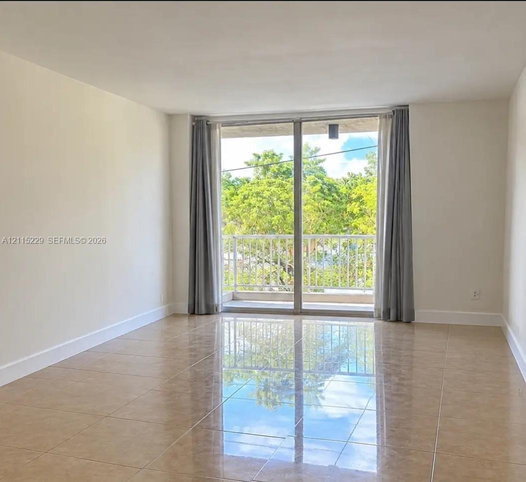 Large-format tile flooring, expansive sliding glass doors, and a private balcony featuring a metal railing