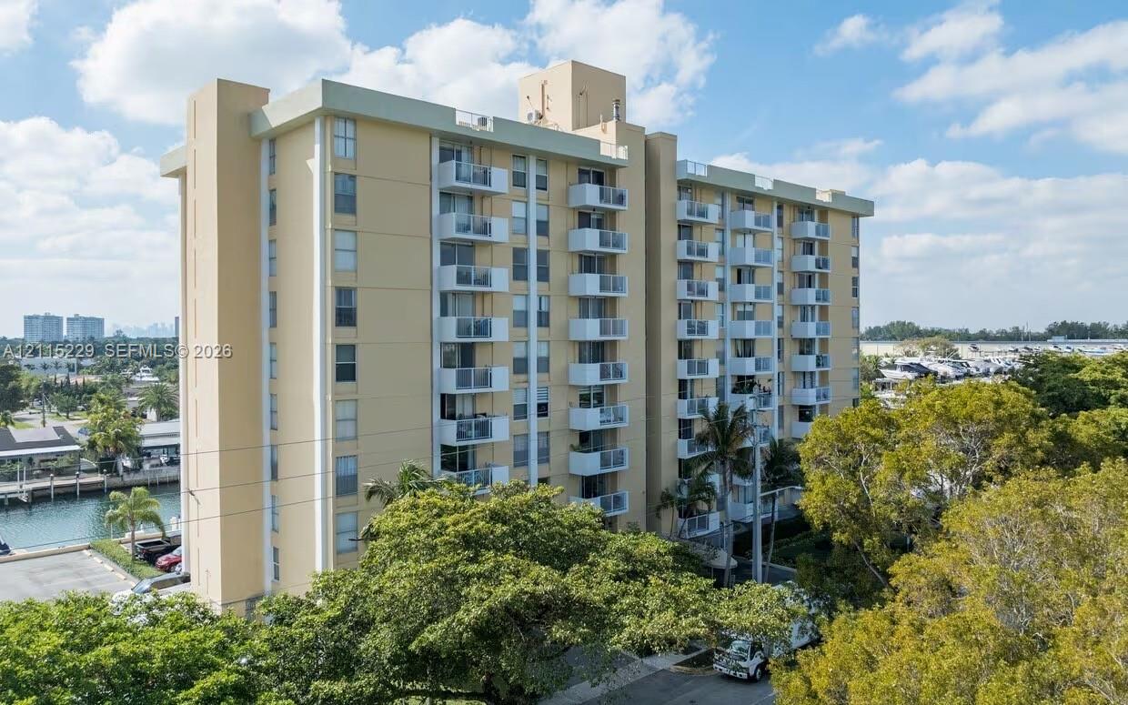 High-rise condominium building featuring multi-level private balconies, smooth exterior cladding, and waterside positioning