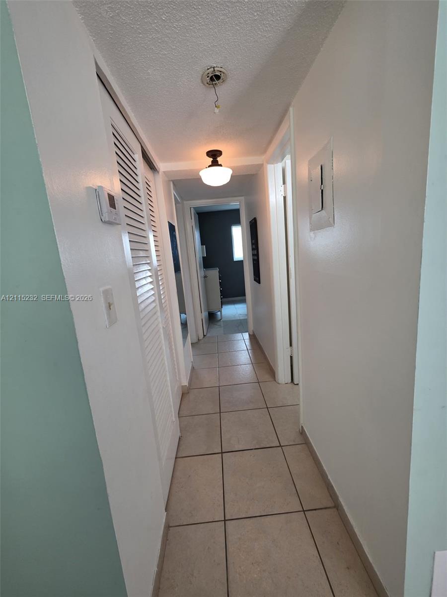 Hallway featuring ceramic tile flooring, built-in louvered-door closet, and semi-flush mount ceiling lighting