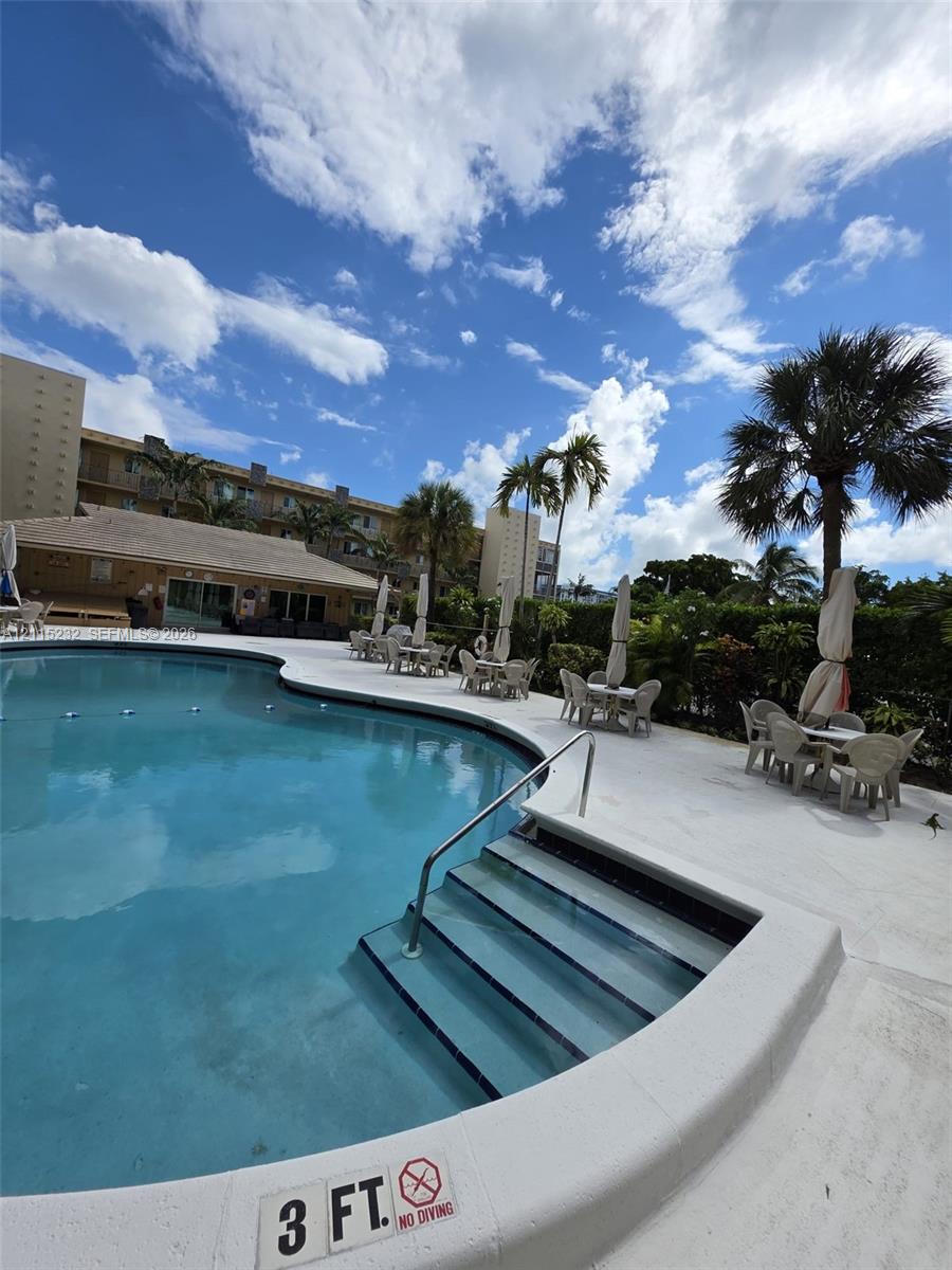 In-ground swimming pool with integrated stair entry, surround concrete decking, and mature landscaping