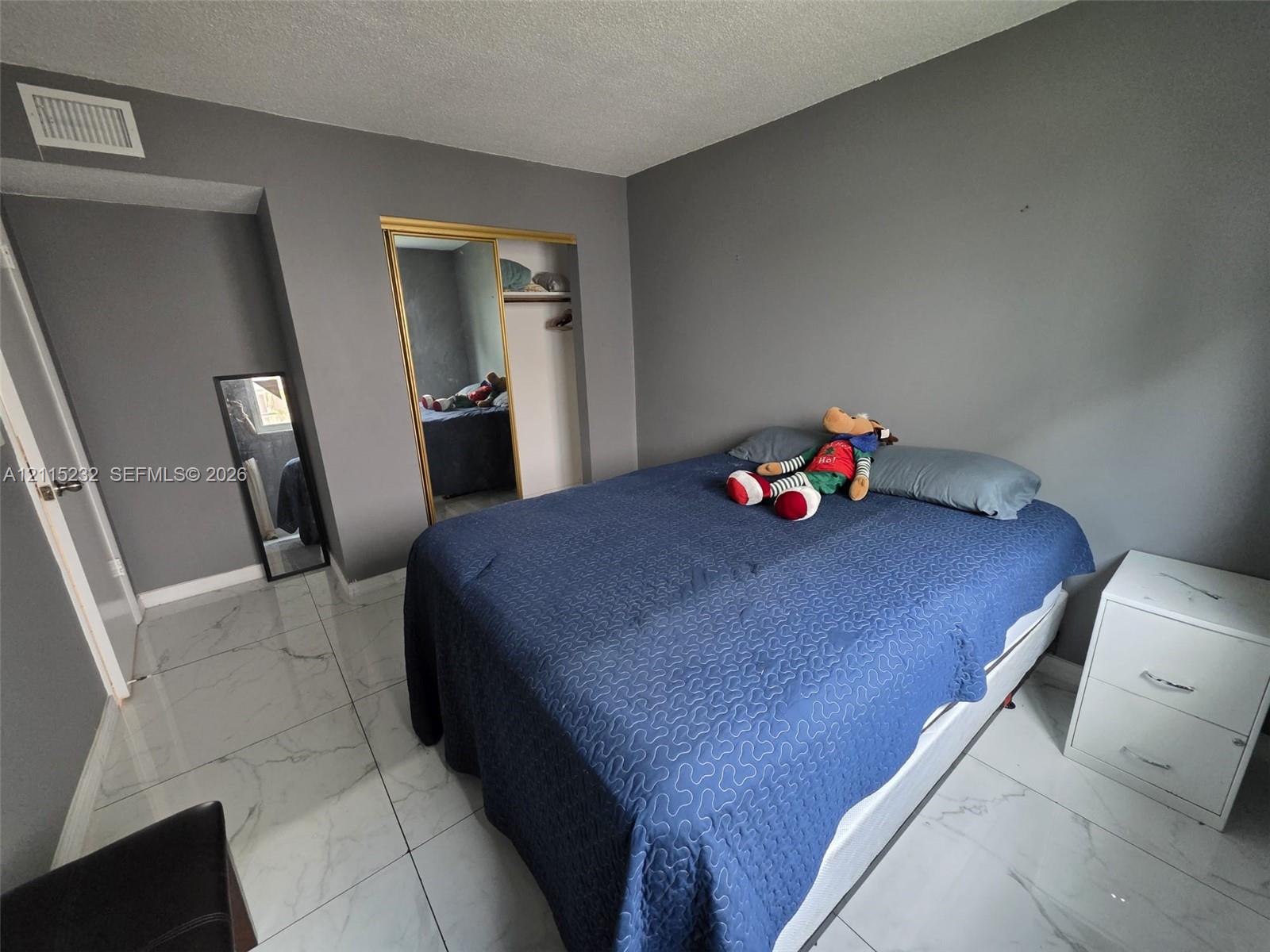 Large-format stone-finish floor tiling, sliding mirrored closet doors, and neutral wall tones