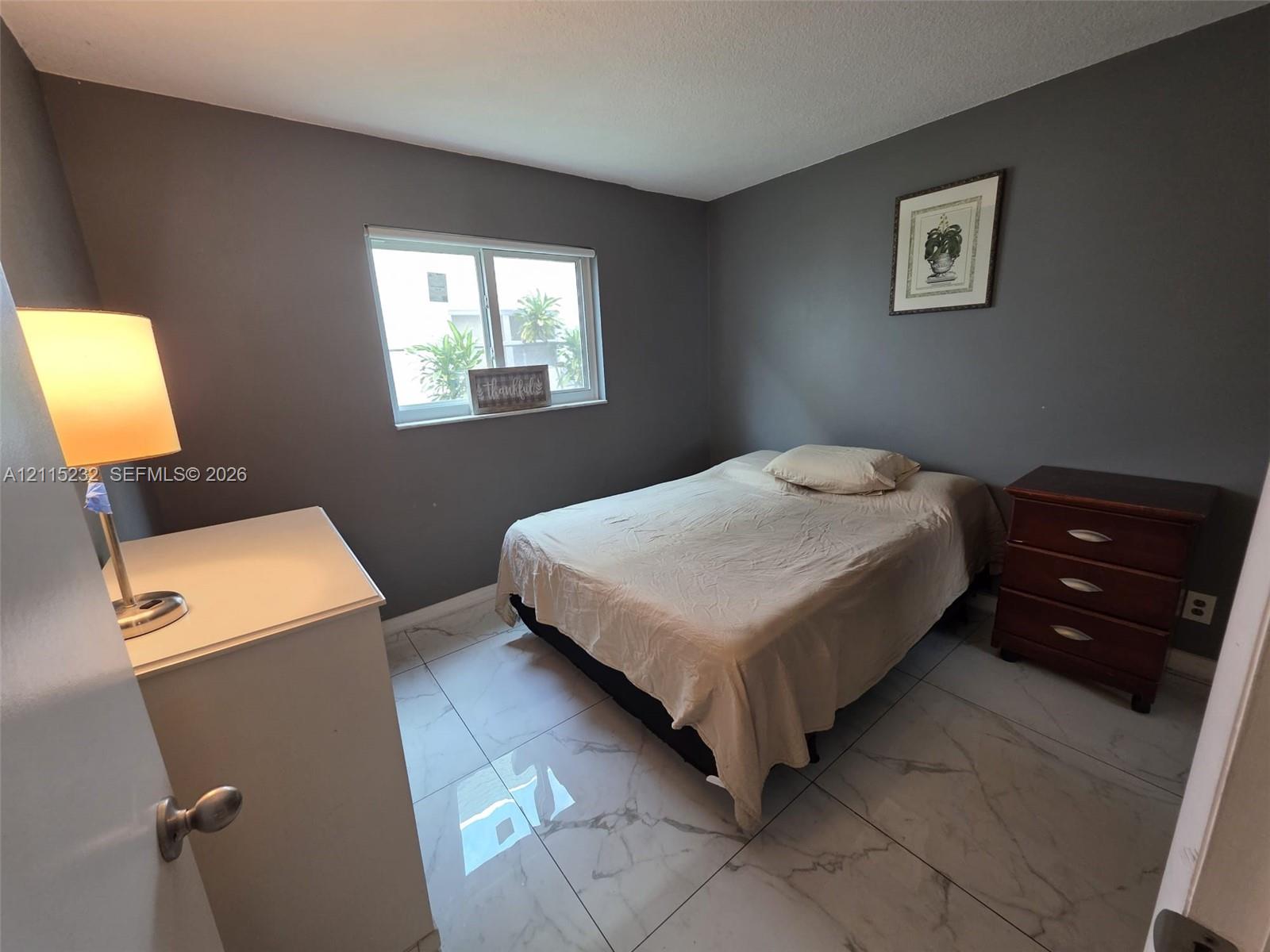 Neutral-toned walls paired with large-format, white marble-patterned tile flooring and a horizontal single-pane window