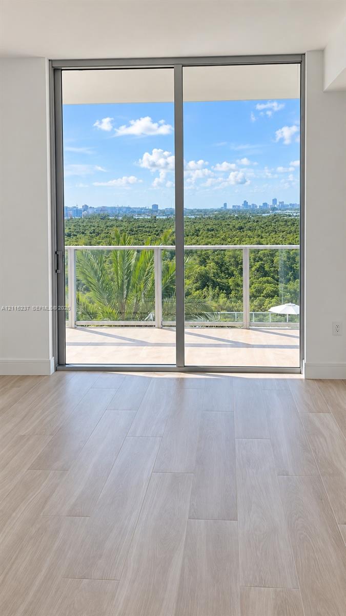Full-height sliding glass doors with aluminum framing, wood-finish flooring, and a private balcony featuring a glass railing