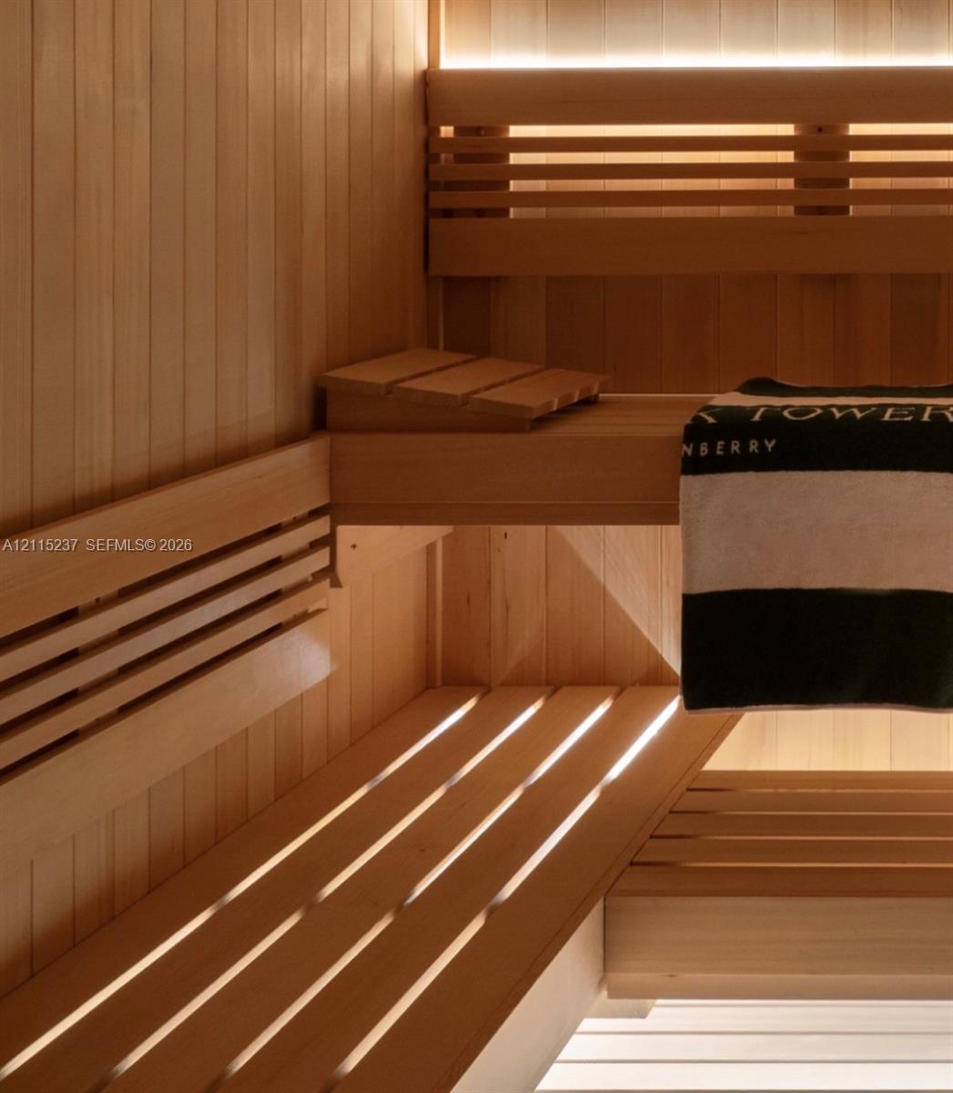 Sauna interior featuring natural wood tongue-and-groove paneling, tiered slatted benches, and integrated recessed accent lighting