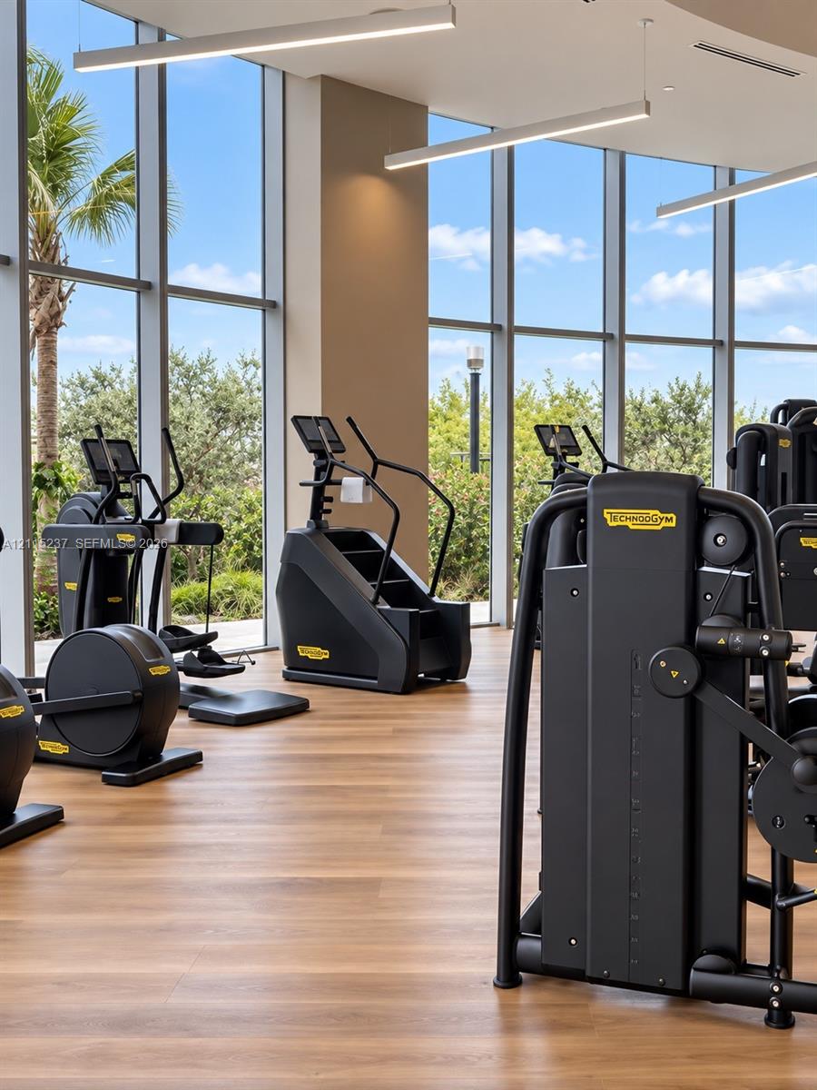 Fitness center featuring floor-to-ceiling windows, wood-finish flooring, and recessed linear pendant lighting