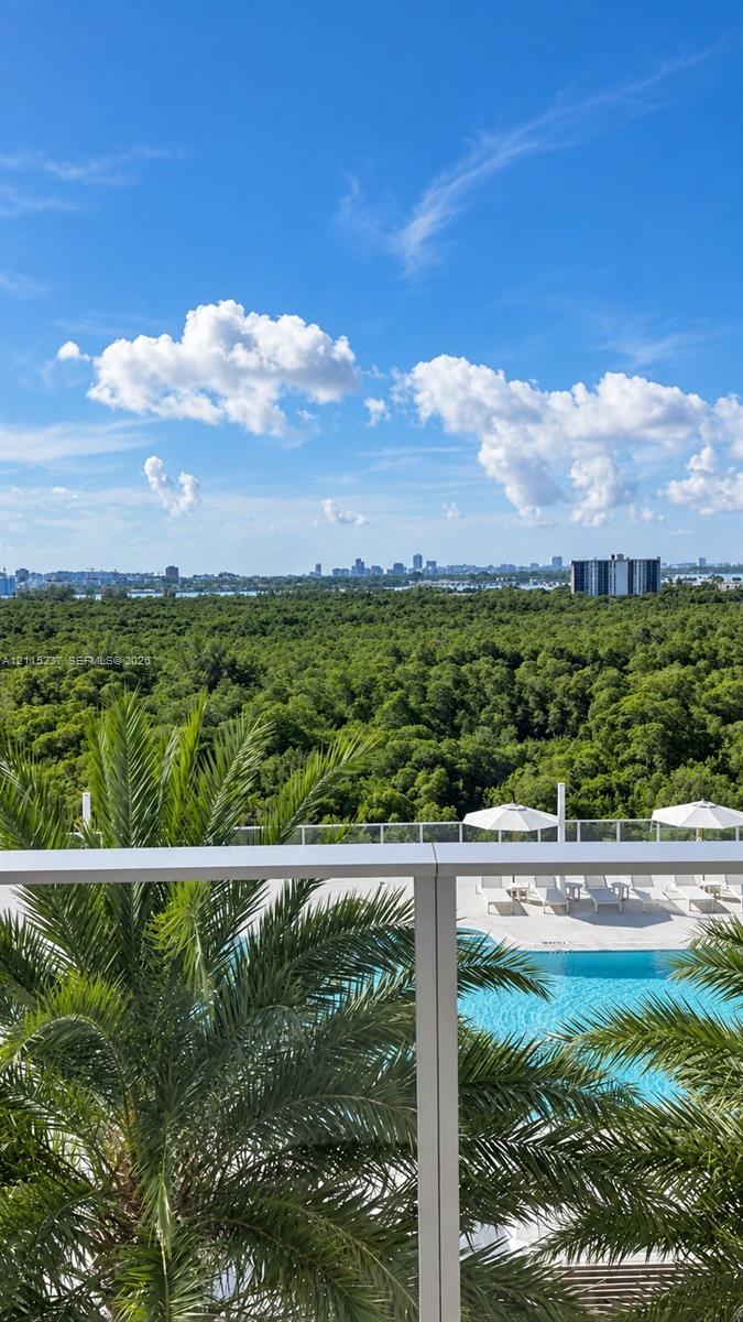 Private balcony with a metal and glass railing, featuring an elevated outlook of a swimming pool, palm trees, and dense forest canopy Private balcony with a metal and glass railing, featuring an elevated outlook of a swimming pool, palm trees, and dense forest canopy