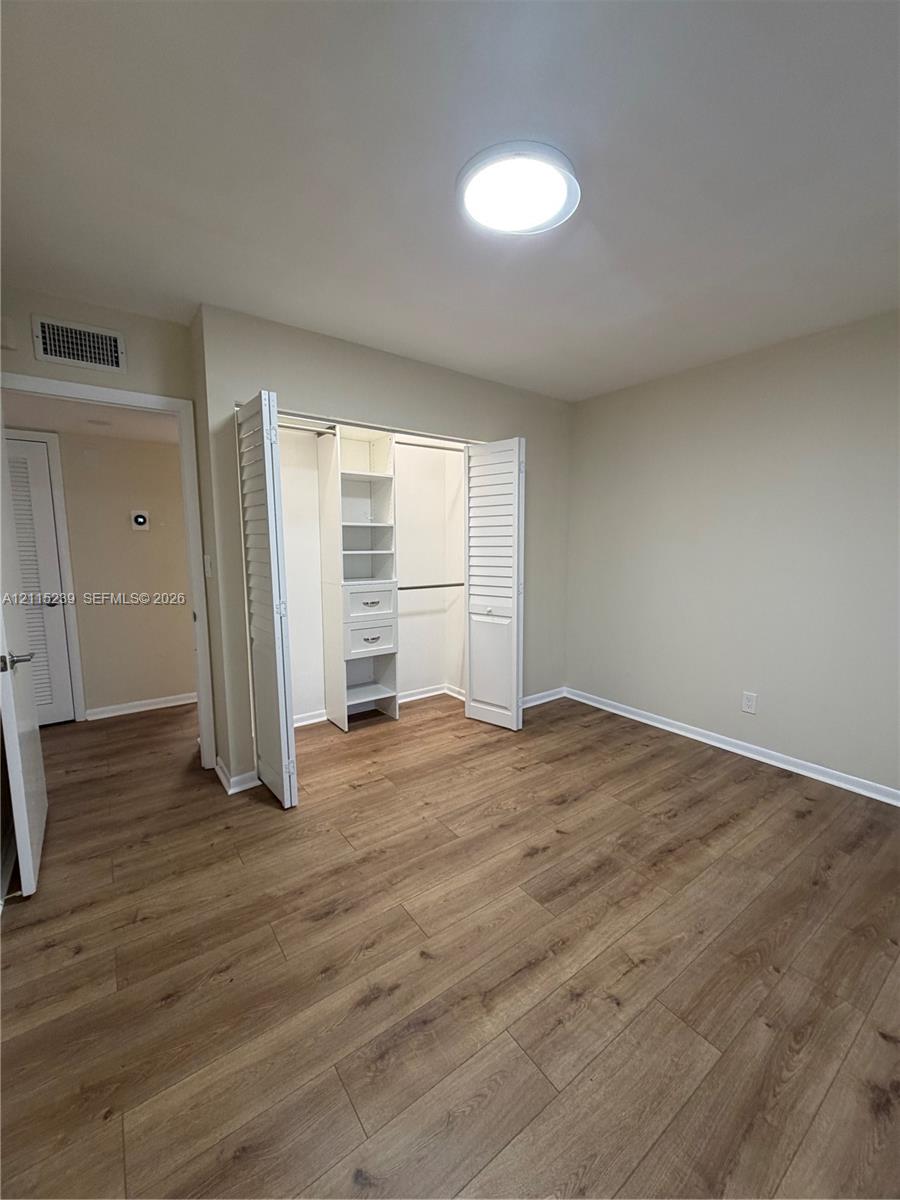 Interior space featuring wood-finish flooring, recessed ceiling lighting, and a closet with bifold louvered doors, built-in shelving, and drawers