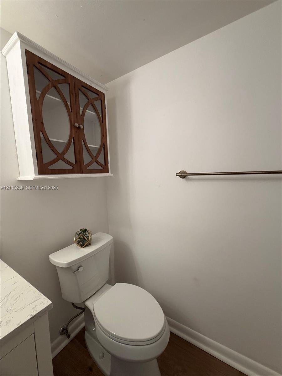 Wall-mounted cabinet with decorative wood-overlay glass doors, stone-finish vanity countertop, and brushed nickel hardware