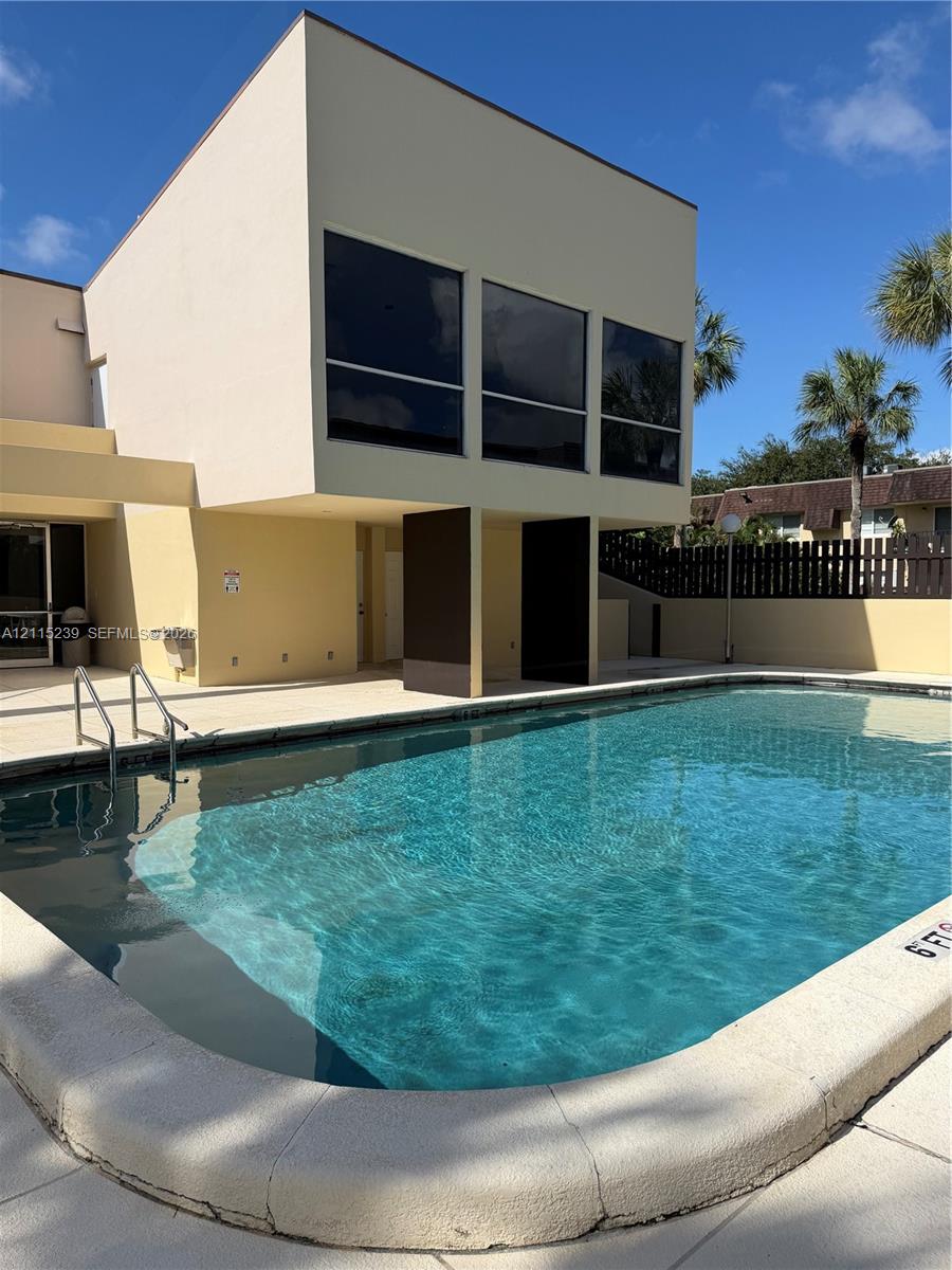In-ground pool featuring a concrete deck, metal handrail, and architectural pillars