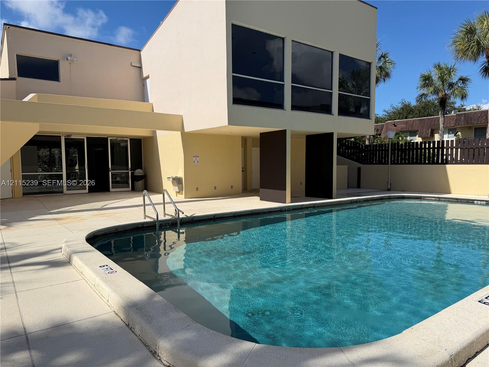 Swimming pool with concrete decking, multi-story exterior architecture, and privacy fencing