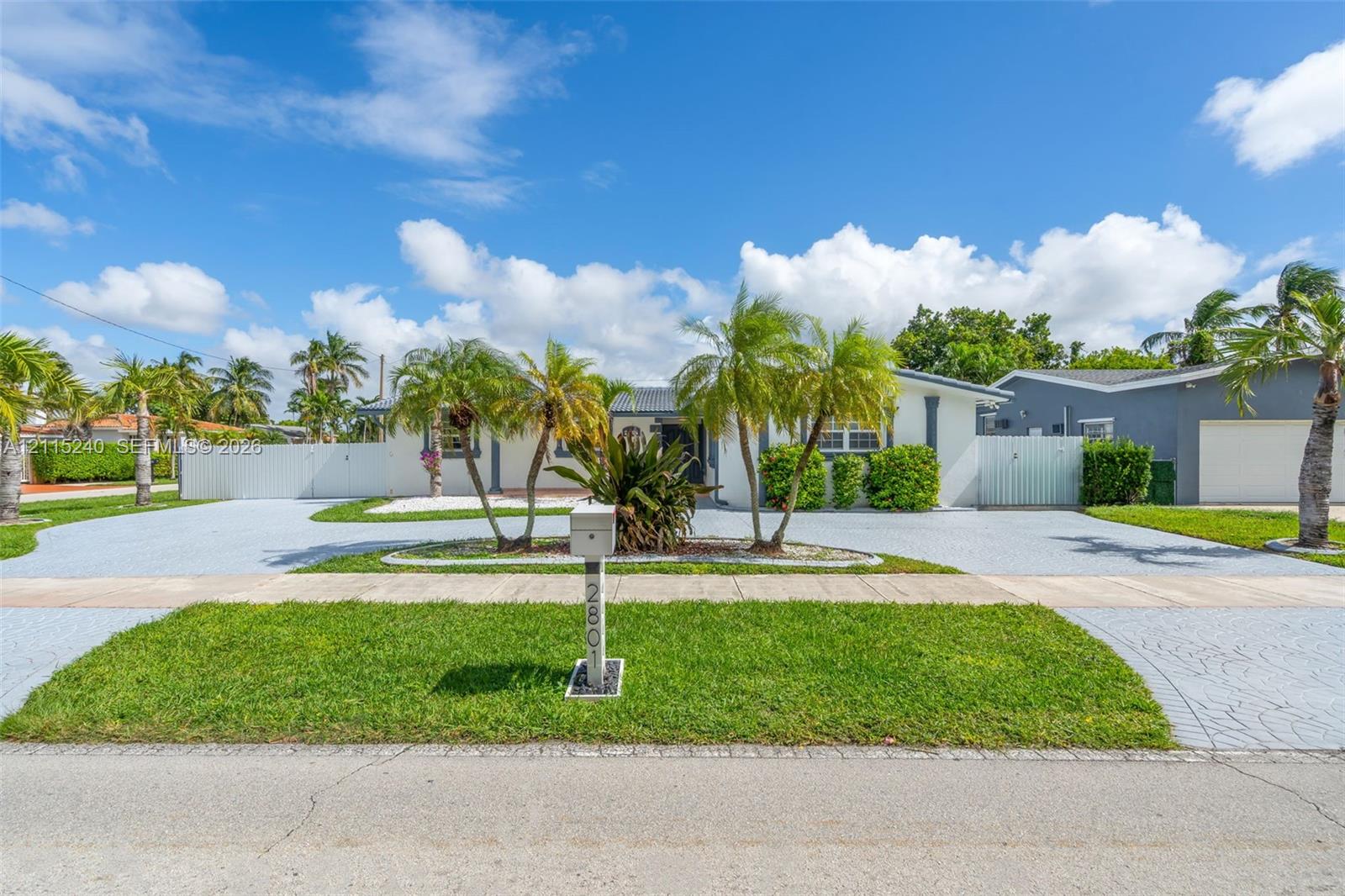 Single-story exterior featuring a stamped concrete driveway, lush palm tree landscaping, and perimeter privacy fencing Single-story exterior featuring a stamped concrete driveway, lush palm tree landscaping, and perimeter privacy fencing