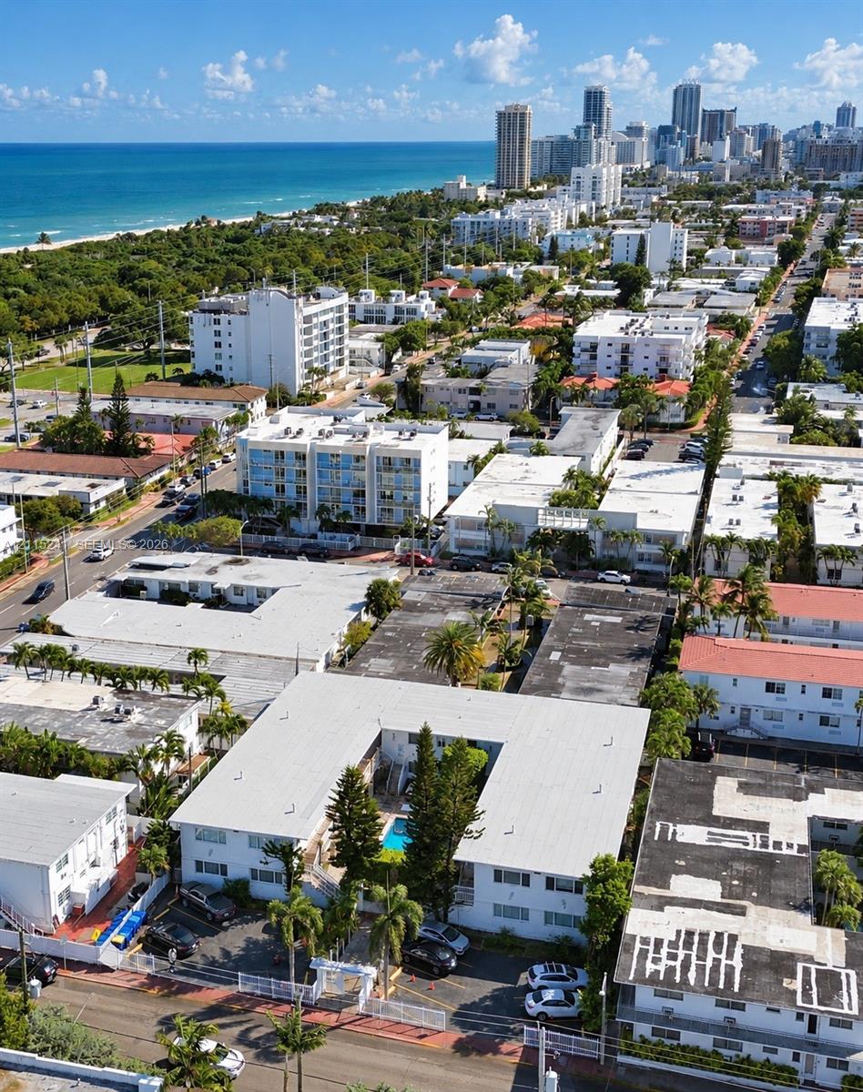 Aerial perspective featuring a multi-unit residential structure with an internal courtyard swimming pool, palm landscaping, and dedicated surface parking