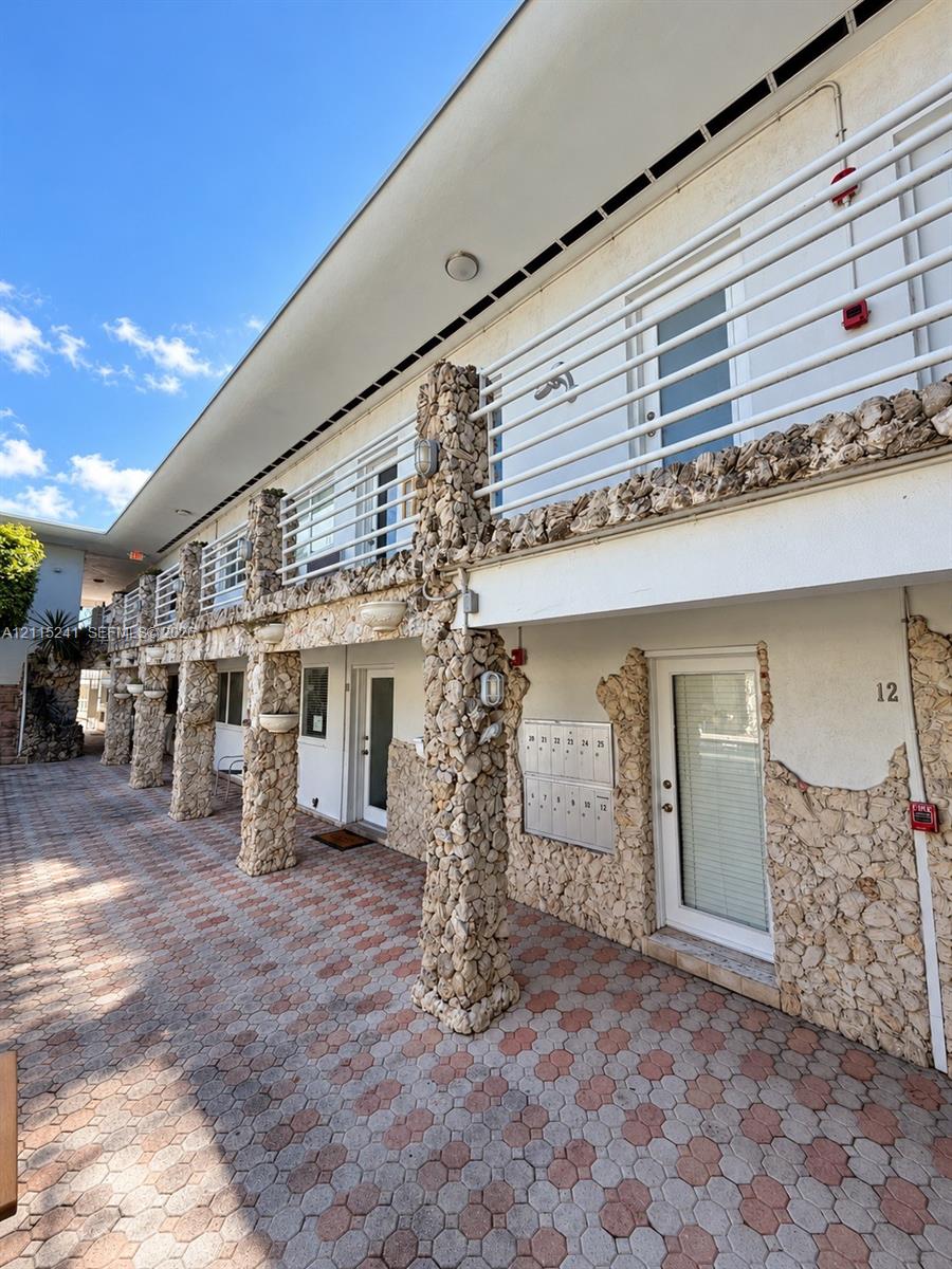 Exterior facade featuring natural stone columns, multi-level walkways, stone masonry accents, a paved patio, and metal railings