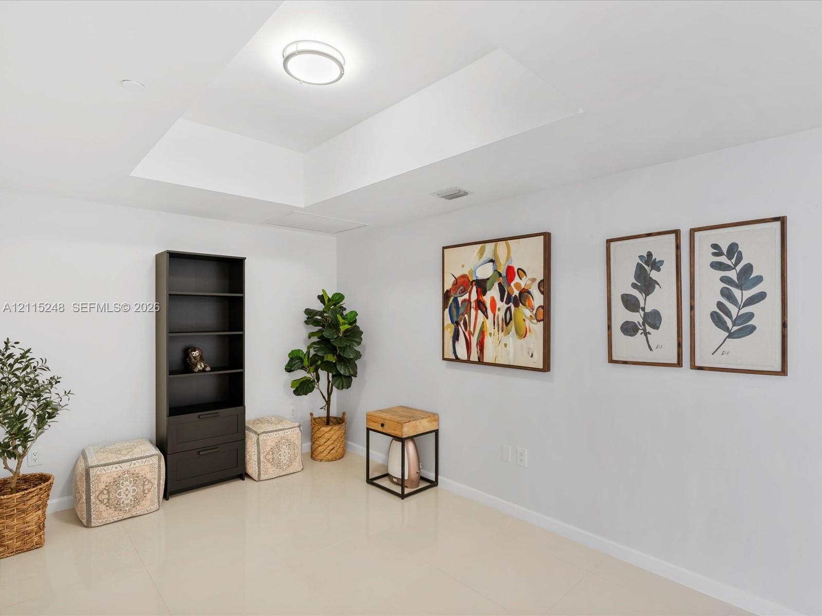 Neutral-toned room featuring a tray ceiling, recessed lighting, and polished stone-finish tile flooring