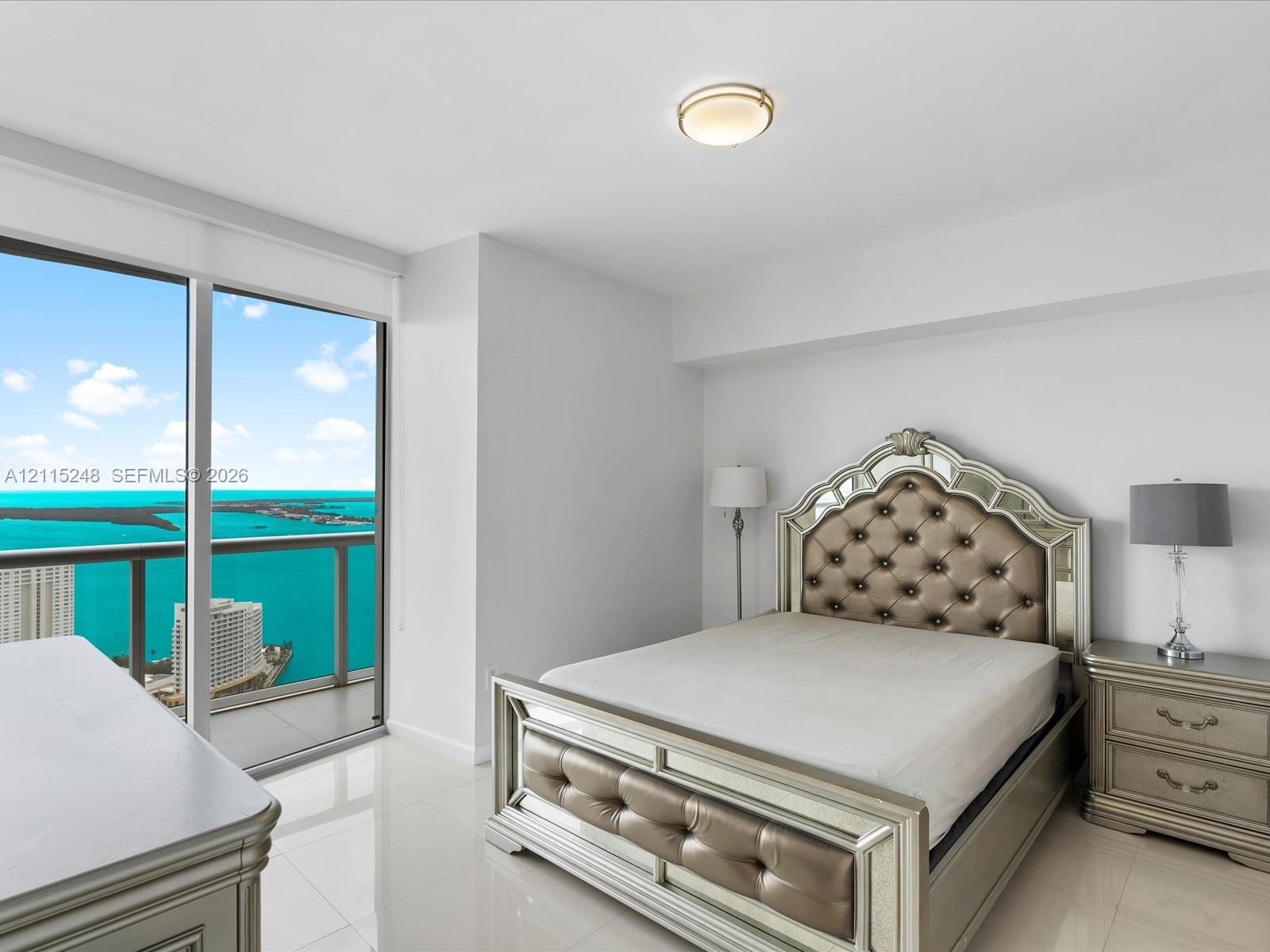 Floor-to-ceiling windows featuring expansive coastal and urban water panoramas, complemented by polished tile flooring and a flush-mount overhead light fixture
