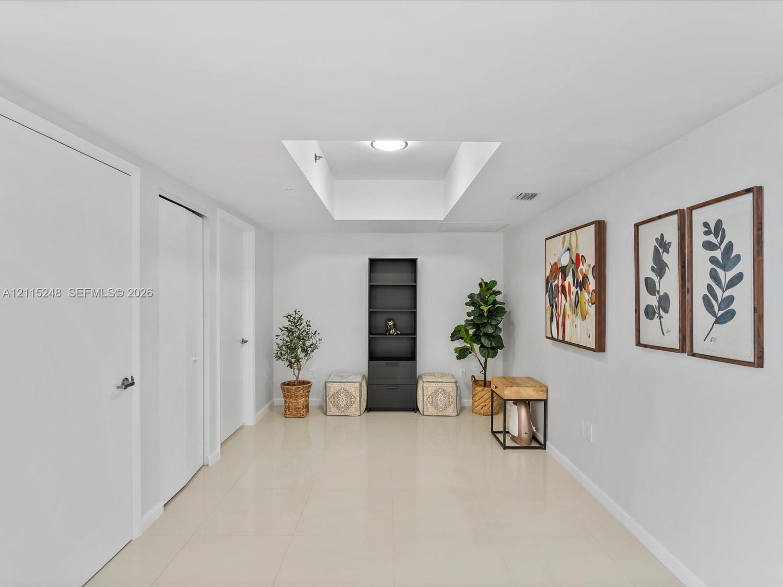 Interior space featuring large-format tile flooring, recessed ceiling lighting, a dedicated rectangular skylight, and multiple interior swing-style doors