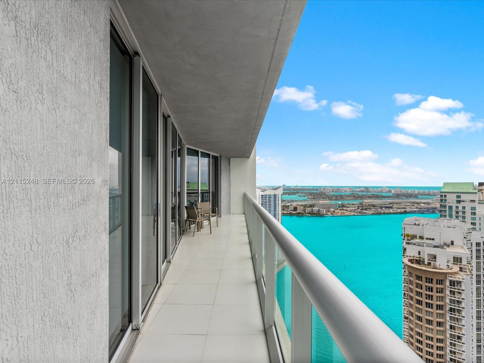 Balcony with large-format tile flooring, glass panel railing, and sliding glass door entry