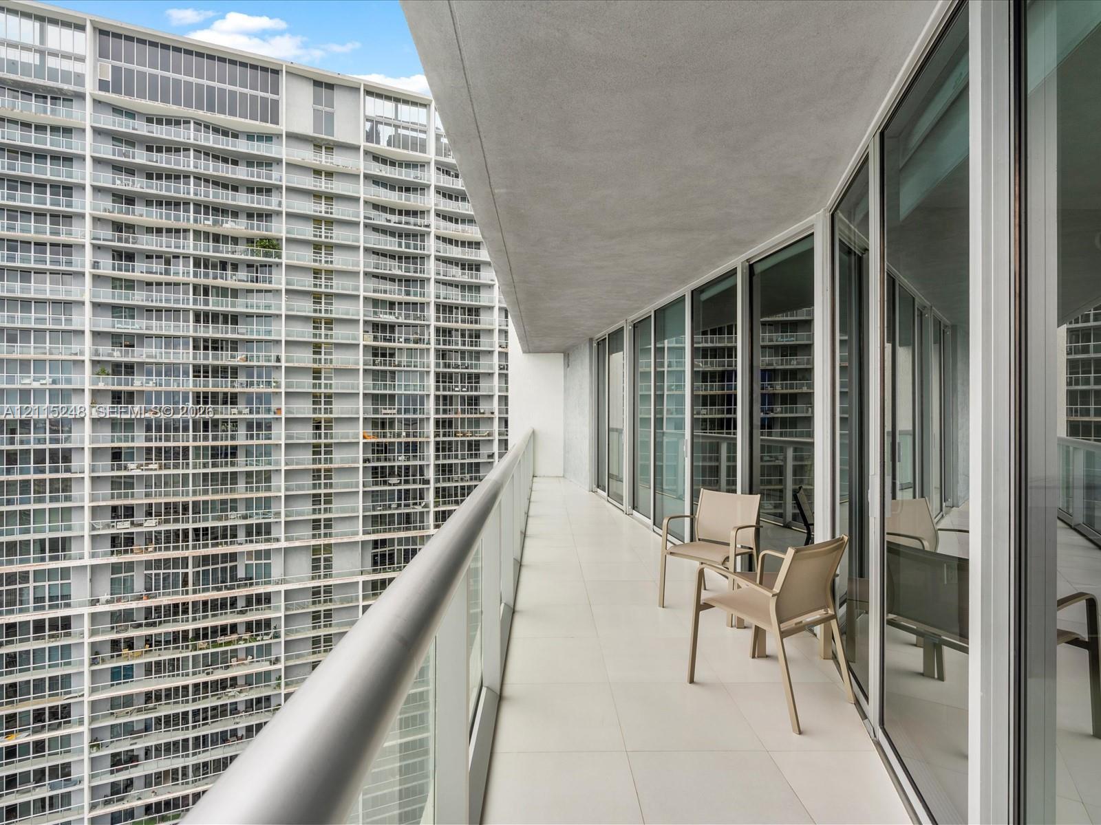 Balcony featuring oversized tile flooring, glass panel railing, and full-height sliding glass doors
