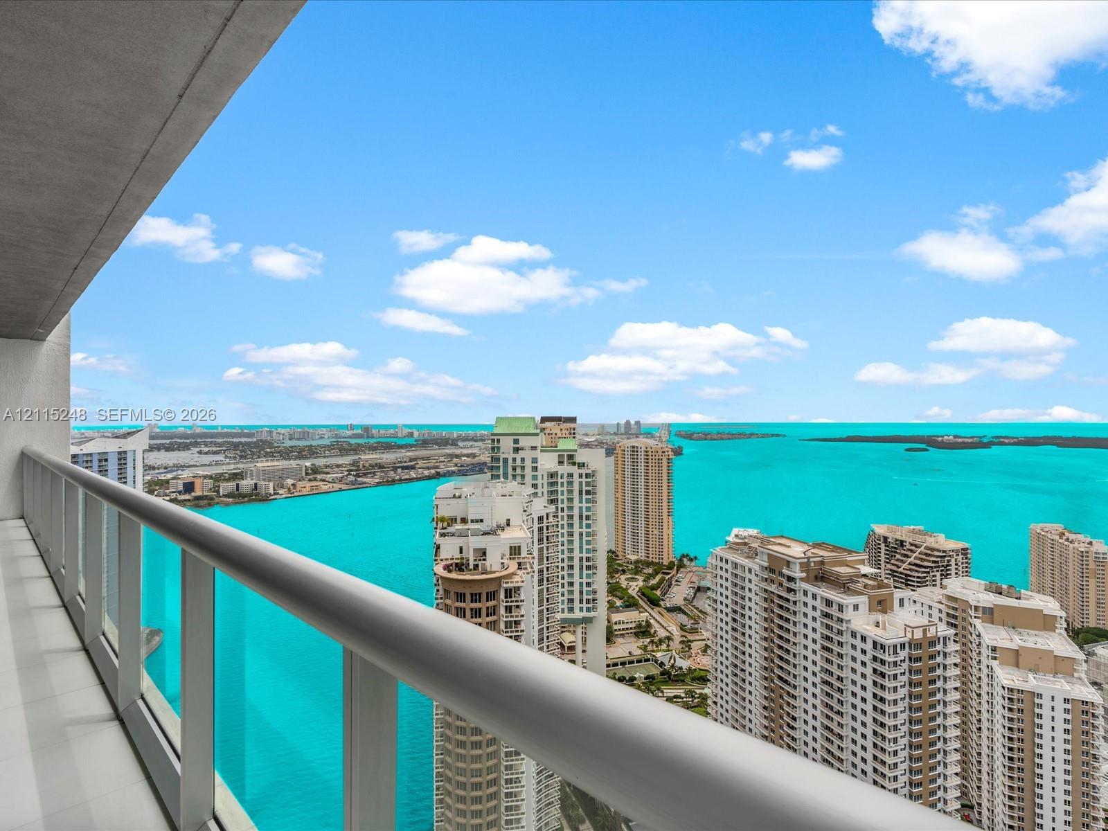 Balcony featuring a sleek metal railing and white tile flooring, offering expansive water and skyline scenery
