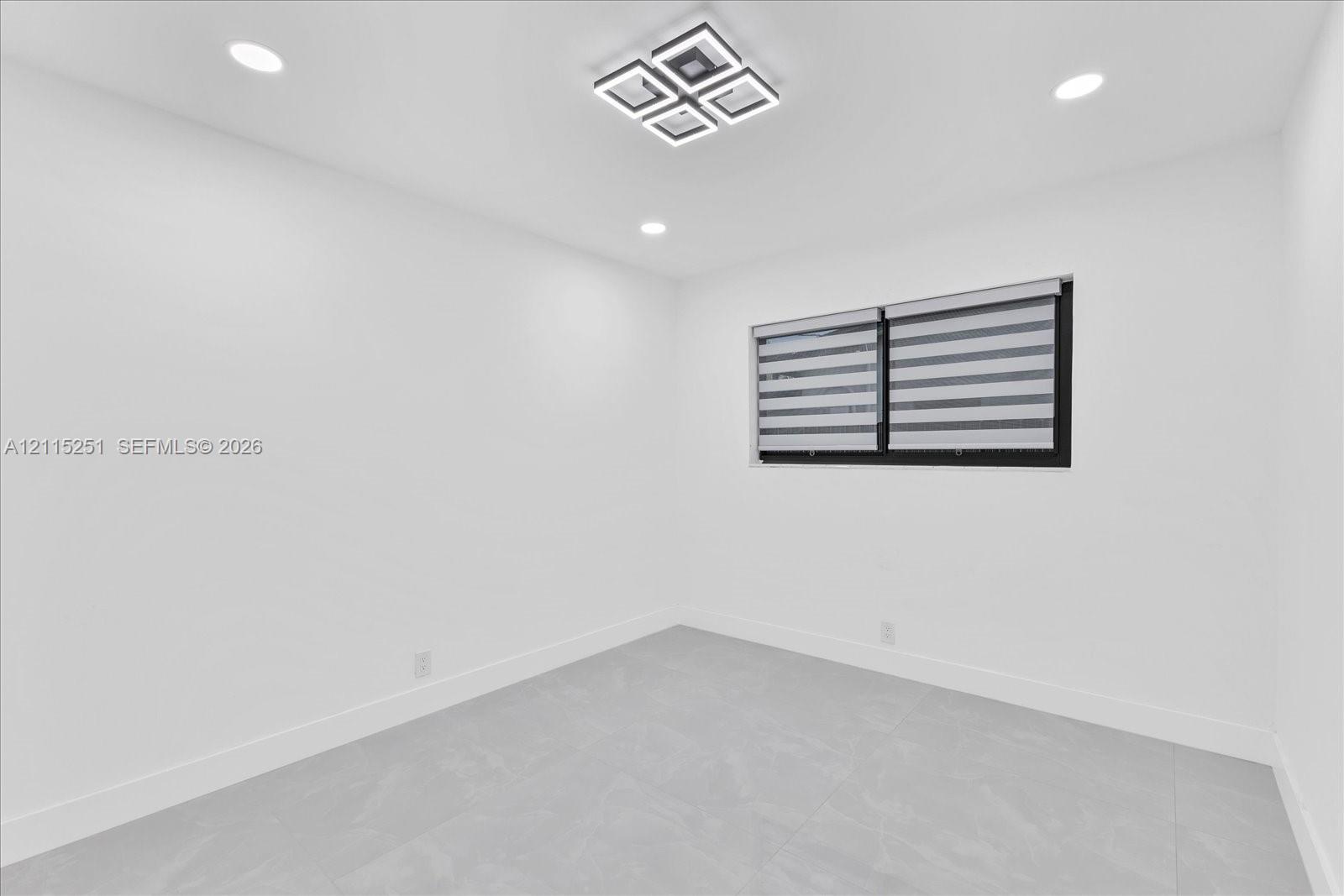 Neutral-toned tile flooring, geometric LED flush-mount lighting, recessed ceiling lights, and window with dark frame