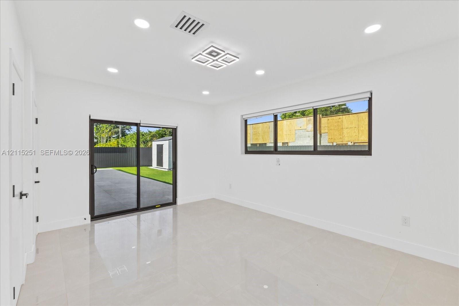 Interior space featuring large-format tile flooring, recessed lighting, a modern geometric ceiling light fixture, sliding glass doors, and a horizontal sliding window
