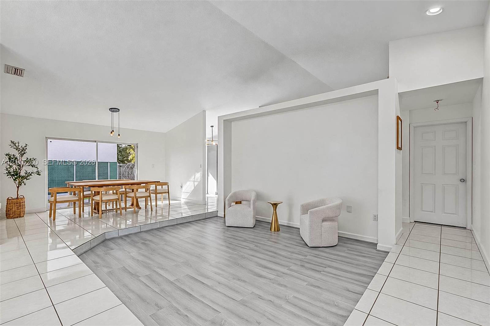 Sunken living area featuring wood-finish flooring, white tile flooring, vaulted ceilings, recessed lighting, and sliding glass doors