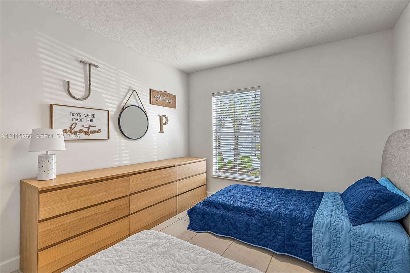 Room featuring neutral walls, large-format tile flooring, and a single-pane window with horizontal blinds