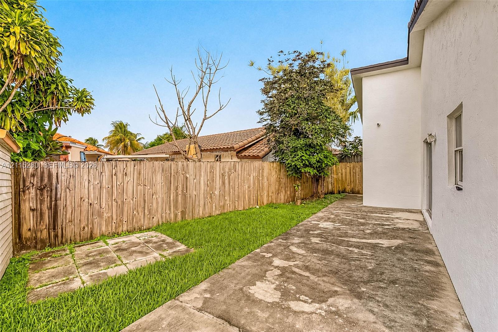 Private backyard featuring a concrete patio, a grass lawn, and wood privacy fencing