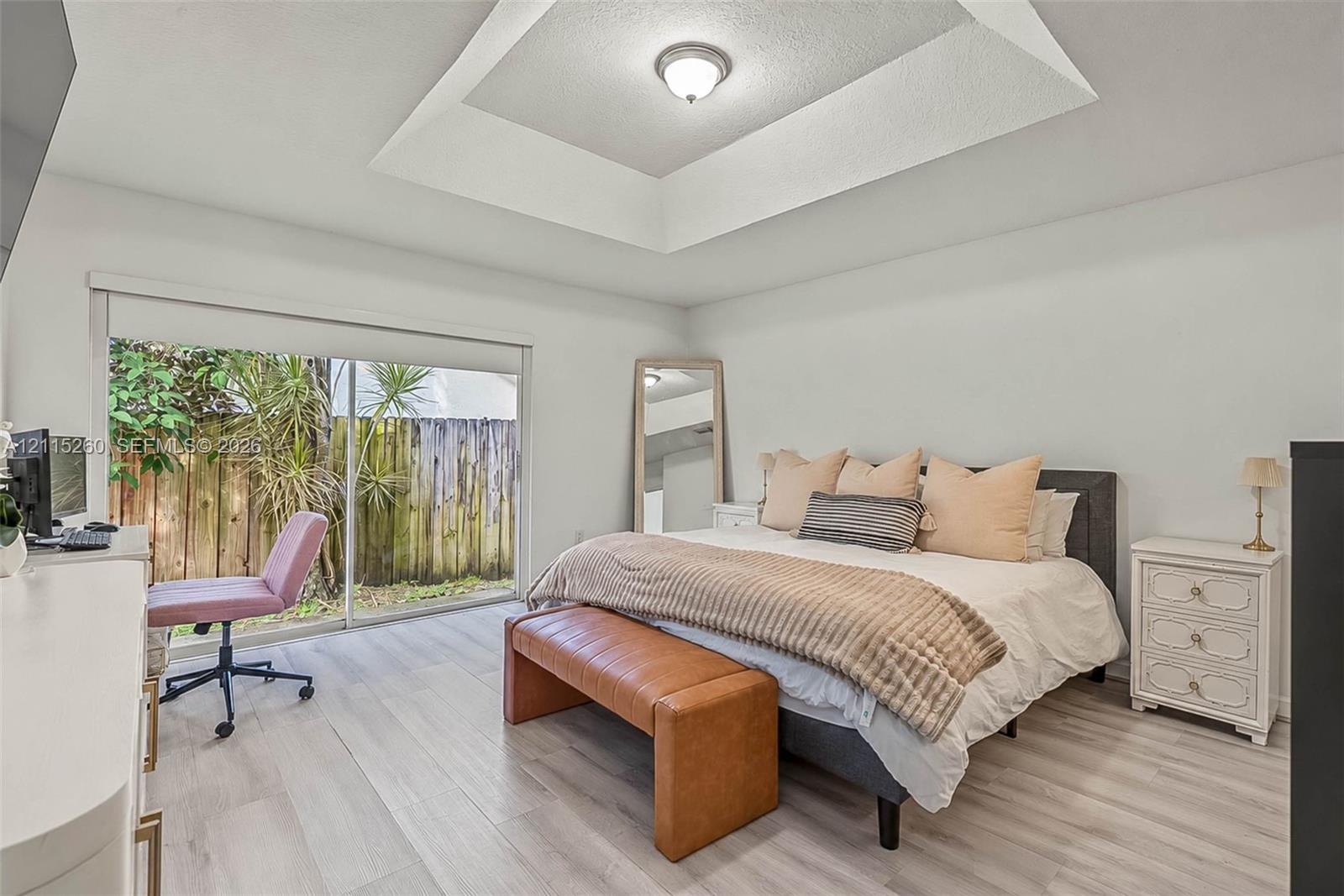 Tray ceiling, wood-finish flooring, and sliding glass doors leading to exterior space