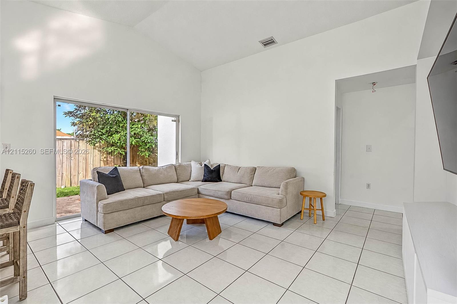 Vaulted ceiling, large sliding glass doors, and polished tile flooring