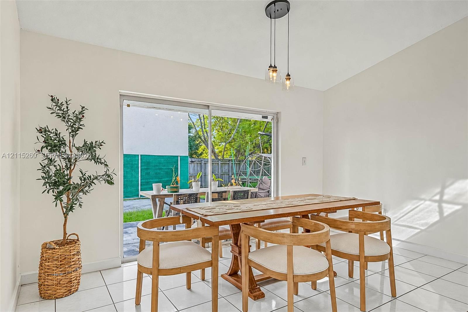 Ceramic tile flooring, multi-light hanging pendant fixture, and large sliding glass door with exterior access