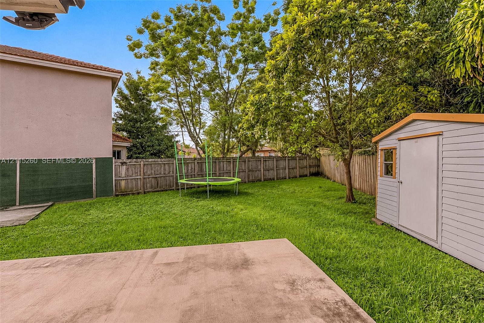Backyard featuring a concrete patio, wood-style privacy fencing, and a detached storage shed
