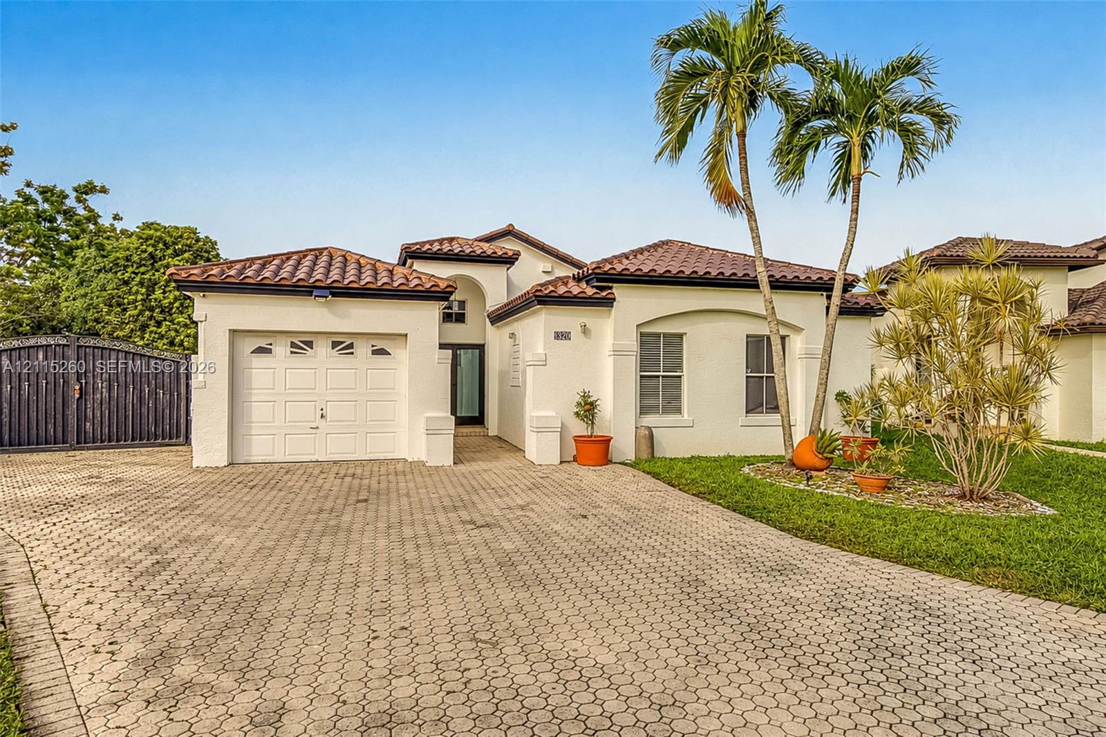 Stucco exterior residence featuring a barrel tile roof, paver driveway, single-car garage, and arched entryway