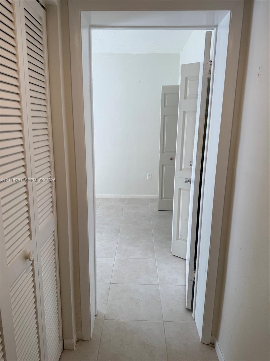 Interior featuring large-format ceramic tile flooring, louvered bi-fold closet doors, and multi-panel interior doors with metallic hardware