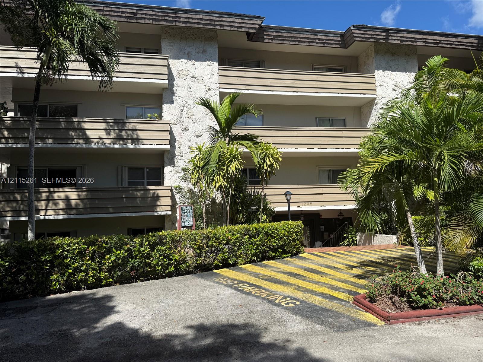 Multi-story exterior featuring stone cladding, horizontal balcony railings, and manicured perimeter landscaping