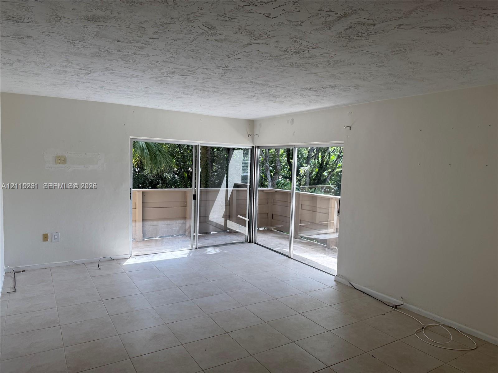 Neutral-toned ceramic tile flooring, dual sliding glass doors, and access to a wood-railed exterior balcony