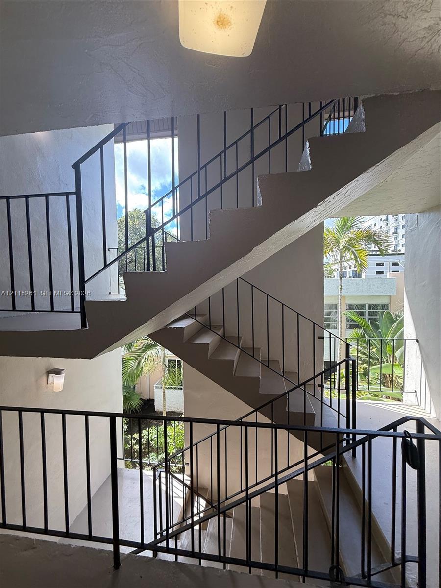 Stairwell featuring concrete steps, geometric black metal railings, and attached exterior lighting