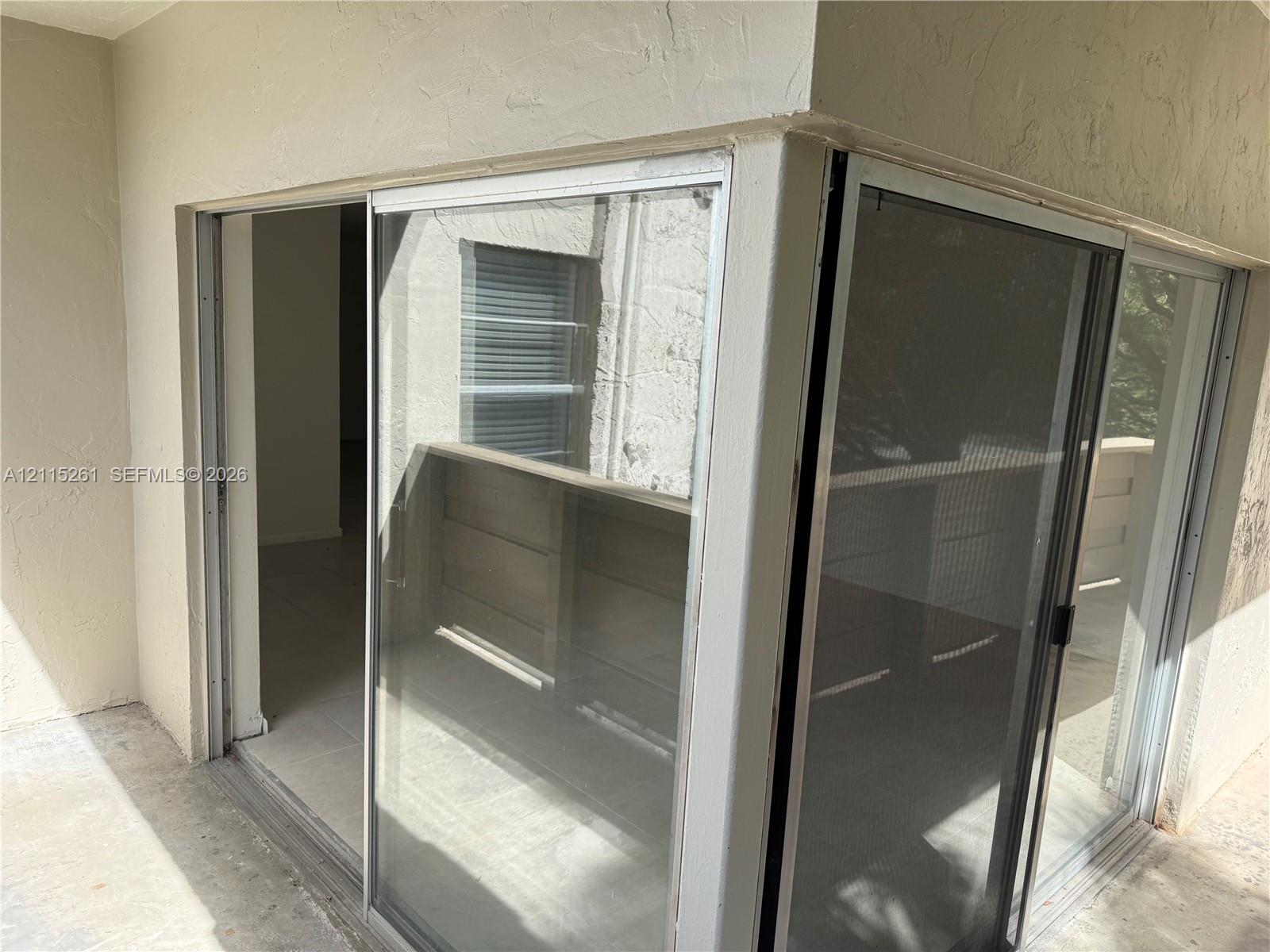 Corner sliding glass door assembly featuring a white frame, integrated screen panels, and neutral-toned stucco exterior finish