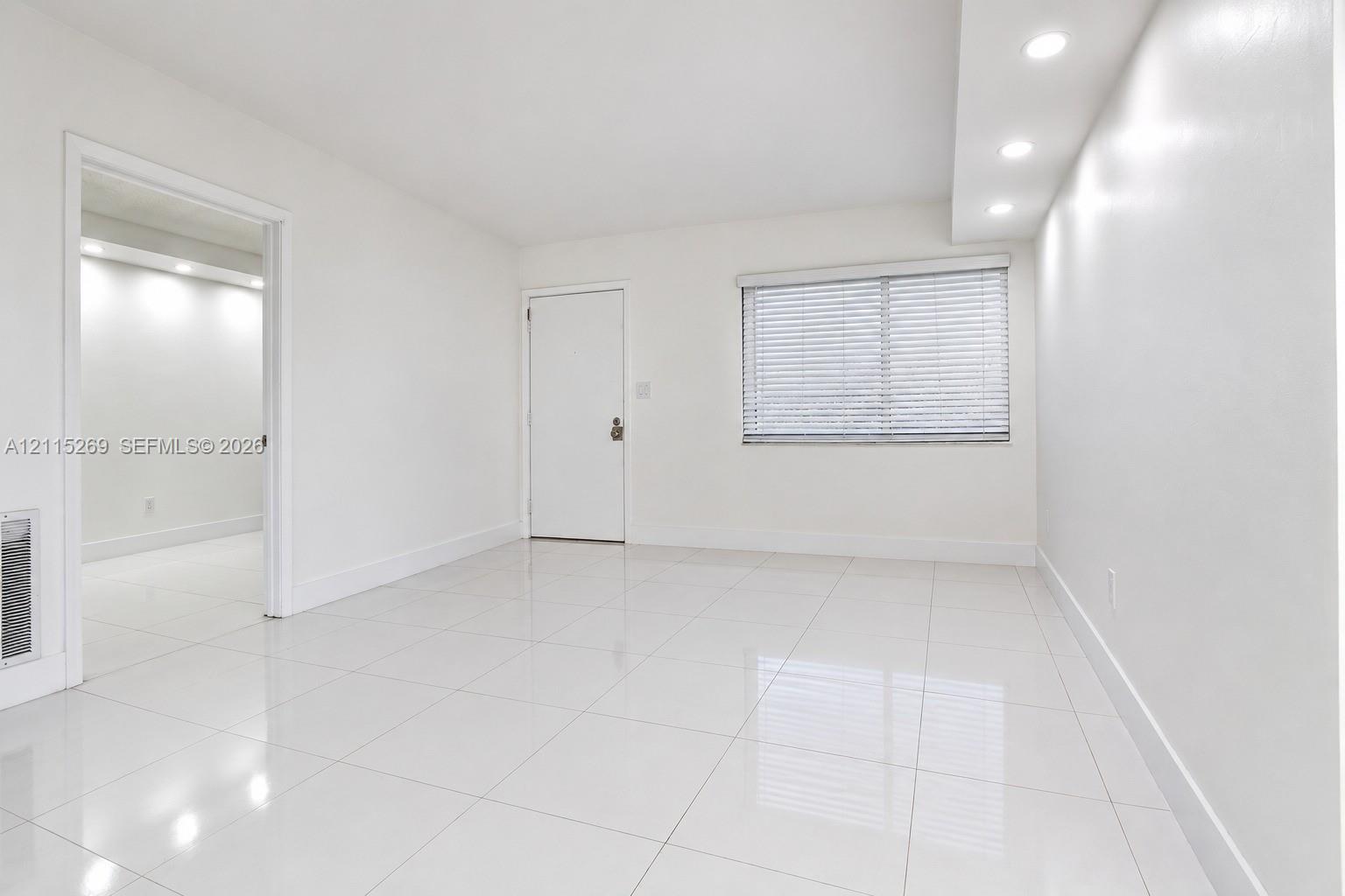 Interior space featuring polished tile flooring, recessed ceiling lighting, and horizontal window blinds