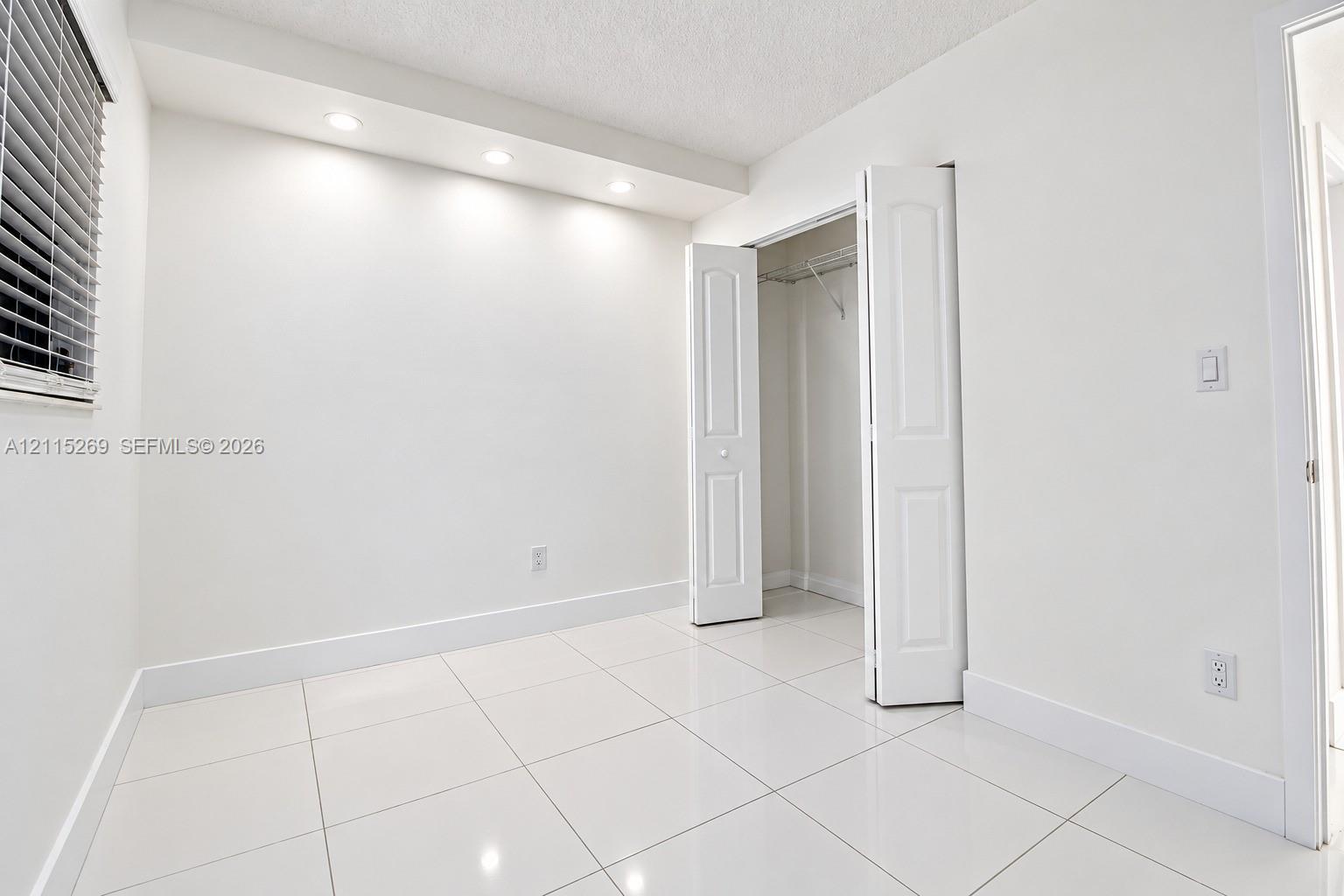 Glossy tile flooring, recessed ceiling lighting, and a closet with bifold doors