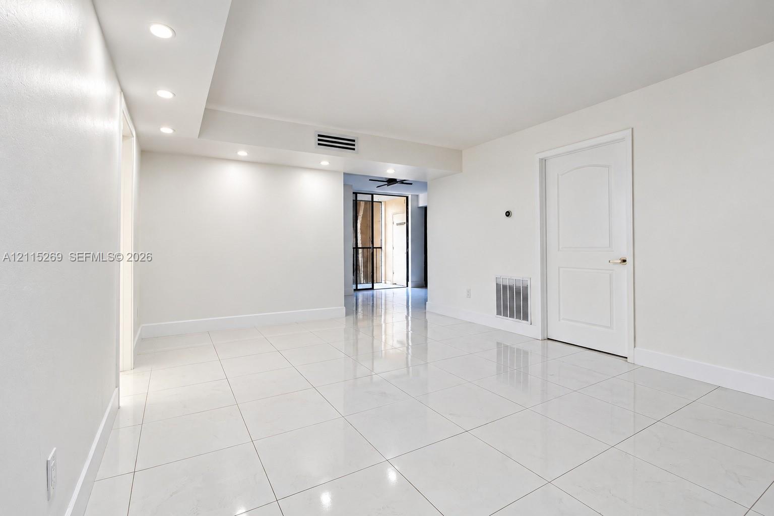 Large-format tile flooring, recessed ceiling lighting, and a solid-core interior door with polished hardware