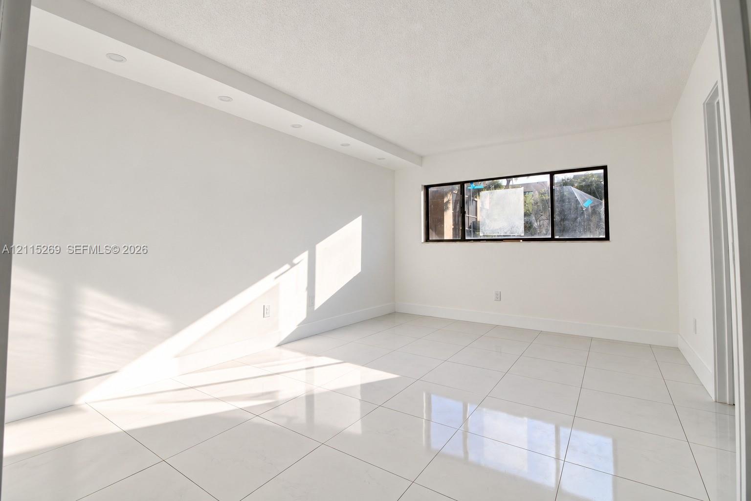 Bright interior space featuring polished tile flooring, recessed ceiling lighting, and a window with a black frame